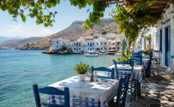 Tradicionalna grčka taverna uz more sa stolovima, plavim stolicama i mediteranskom atmosferom.